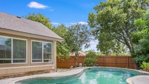 Un patio trasero con piscina, una casa y una cerca de madera.