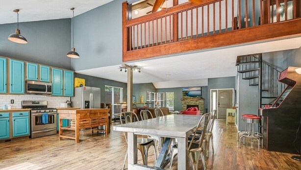 Una cocina amplia con armarios de madera, una mesa de comedor y una escalera que sube a un nivel superior.