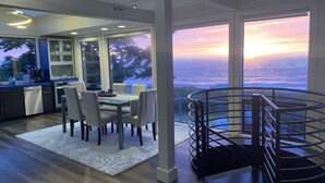 A modern kitchen with a dining area, large windows, and a spiral staircase. - Bodega Bay - Magical Ocean Front View- Doesn’t get better than this!! (Bodega Bay)