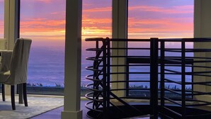 A room with a view of a sunset over the ocean, a chair, and a metal railing. - Bodega Bay - Magical Ocean Front View- Doesn’t get better than this!! (Bodega Bay)