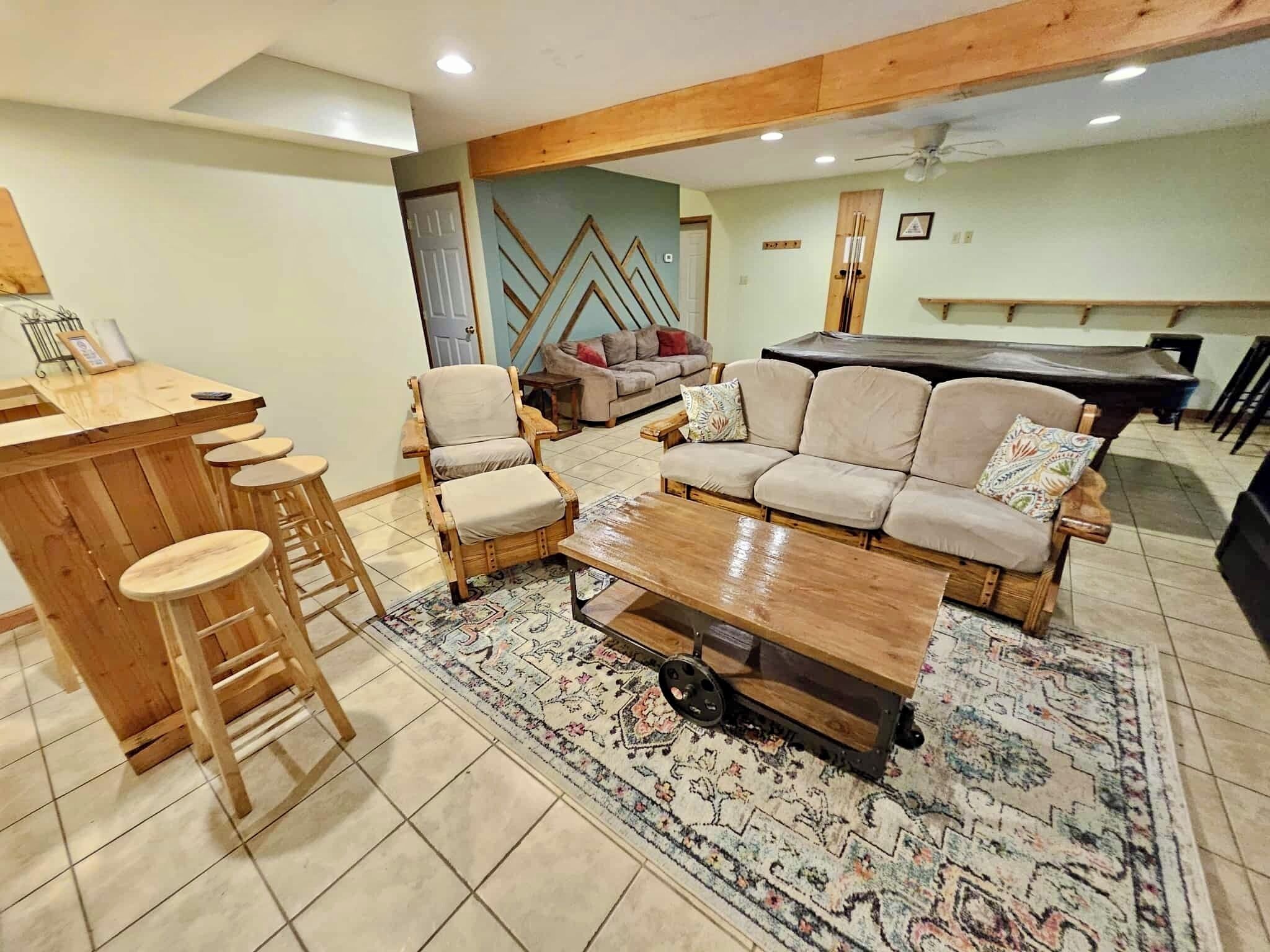 A living room with a wooden bar, a sofa set, and a patterned rug.