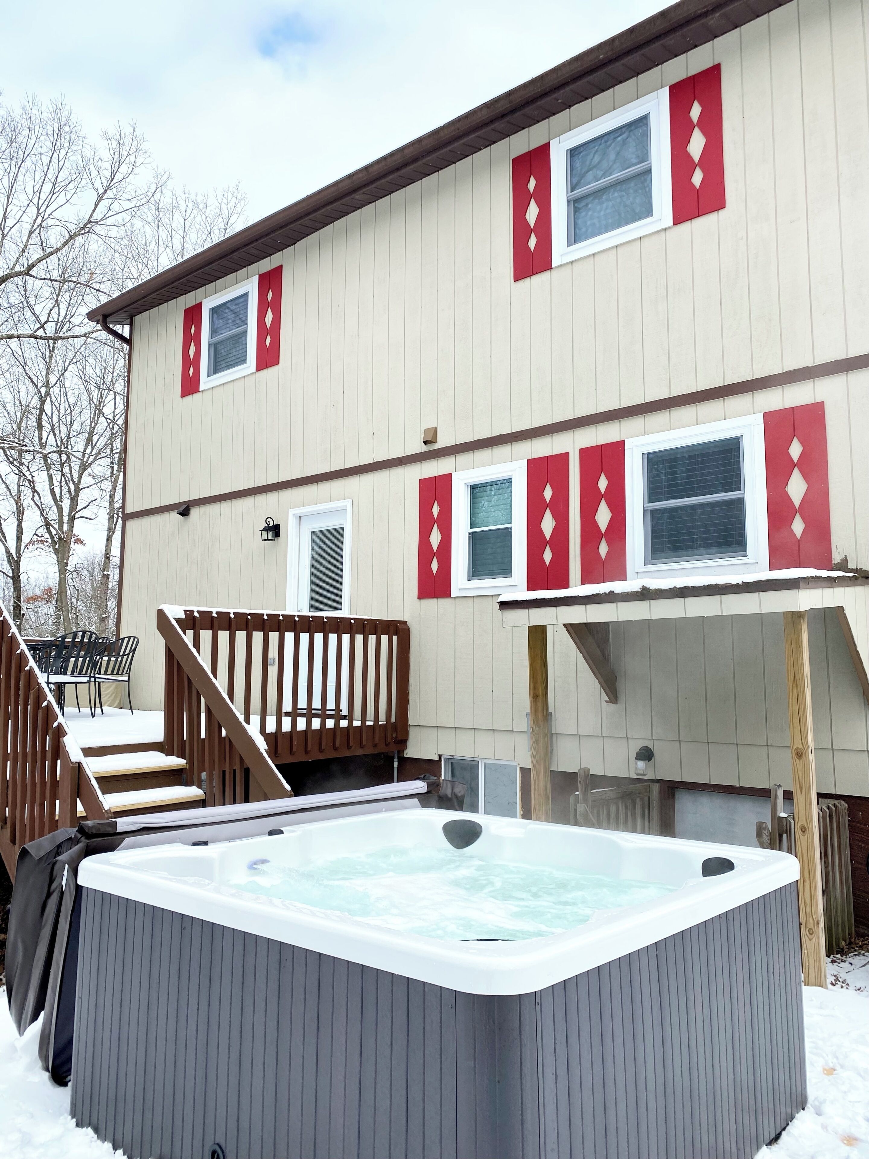 Una casa de dos pisos con un jacuzzi en el patio trasero.