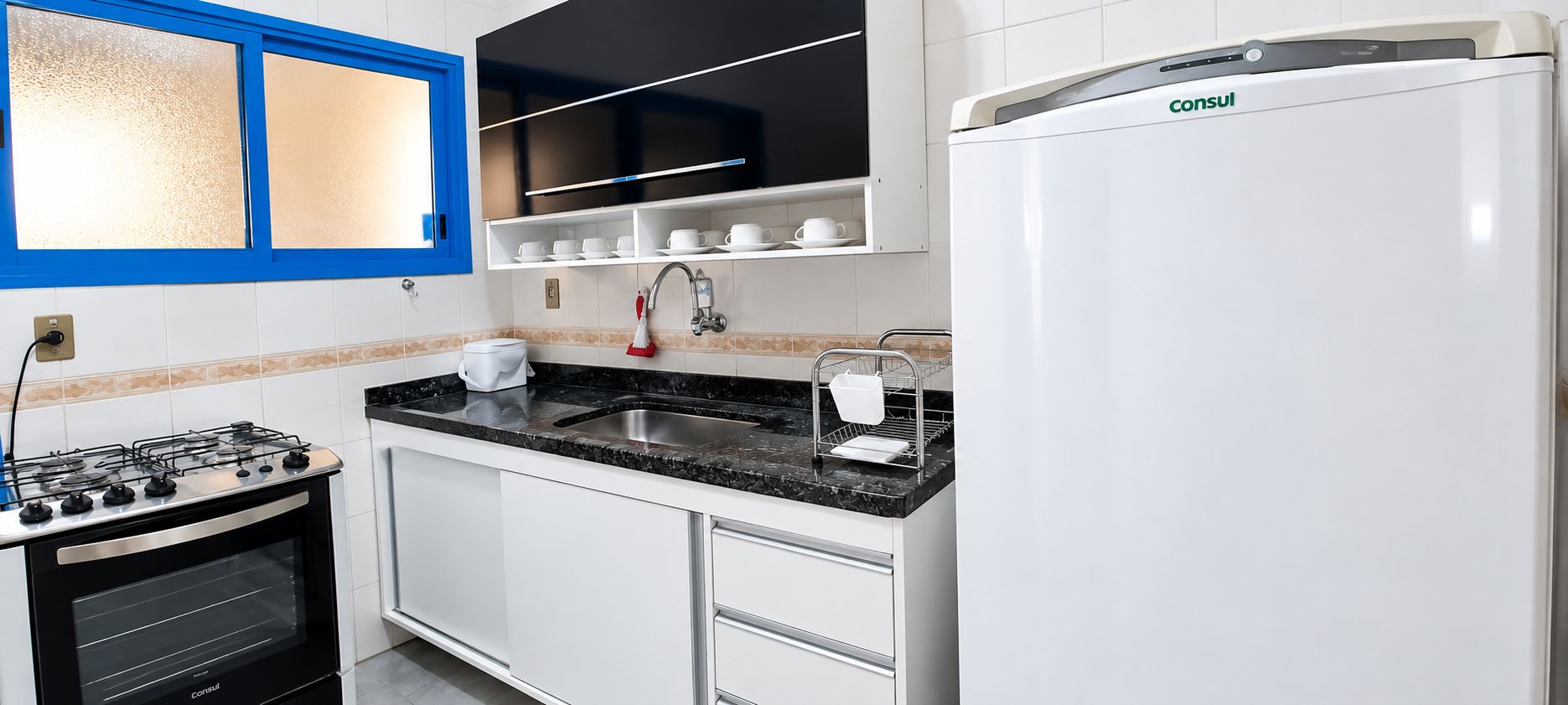 Una cocina moderna con estufa a gas, horno integrado, pileta y refrigerador.