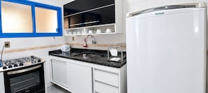 Una cocina moderna con estufa a gas, horno integrado, pileta y refrigerador.