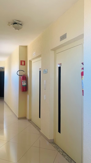 Käytävä, jossa on kolme ovea, palosammutin ja kattovalaisin.