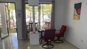 A spacious room with a large window, a ceiling fan, and a red chair. - Rita & Sonny Beach Apt-B (Tamarindo-Playa Callejones)