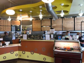 A cafe interior with a counter, menu boards, and a beverage display. - Charming Carriage House In Prospect New Town (Longmont)