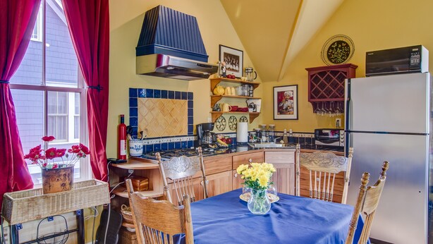A kitchen with a dining area, featuring a stove, microwave, refrigerator, and various kitchen utensils. - Charming Carriage House In Prospect New Town (Longmont)