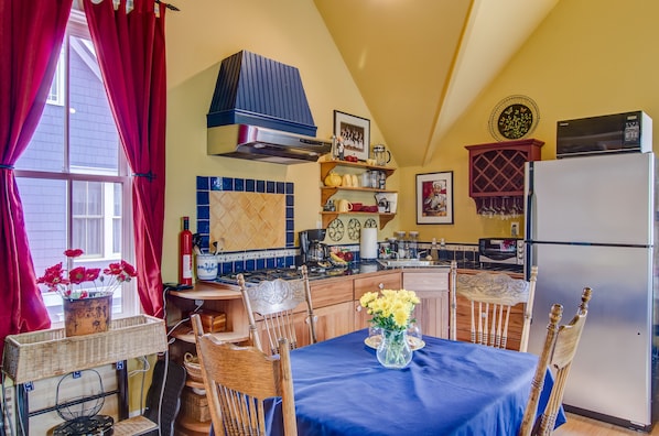 A kitchen with a dining area, featuring a stove, microwave, refrigerator, and various kitchen utensils. - Charming Carriage House In Prospect New Town (Longmont)