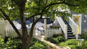 A garden pathway leading to a house with a white picket fence, a staircase, and a yellow door. - Charming Carriage House In Prospect New Town (Longmont)