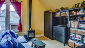 A cozy living room with a fireplace, a bookshelf, and a comfortable sofa. - Charming Carriage House In Prospect New Town (Longmont)