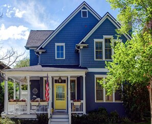 A two-story house with a blue exterior, a yellow front door, and a porch with white railings. - Charming Carriage House In Prospect New Town (Longmont)