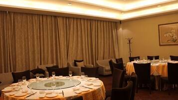 A dining area with round tables, chairs, and a large curtain backdrop.