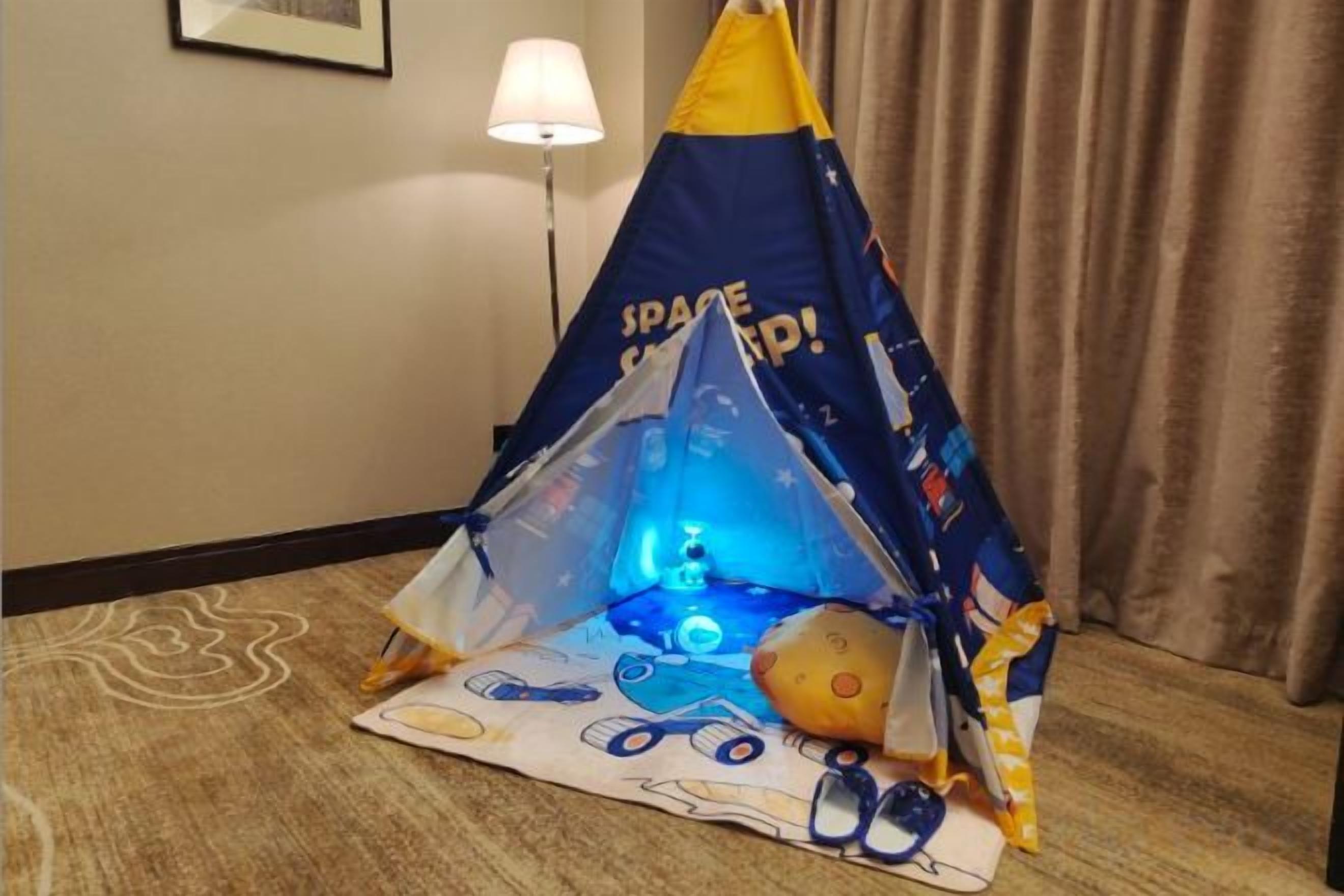 Une tente de jeu sur le thème de l’espace, avec une lumière à l’intérieur, placée sur un sol recouvert d’une moquette.