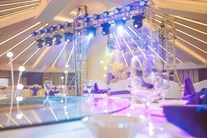 A stage with a metal frame and spotlights, surrounded by tables with floral centerpieces. - ZTE Hotel, Nanjing (Nanjing)