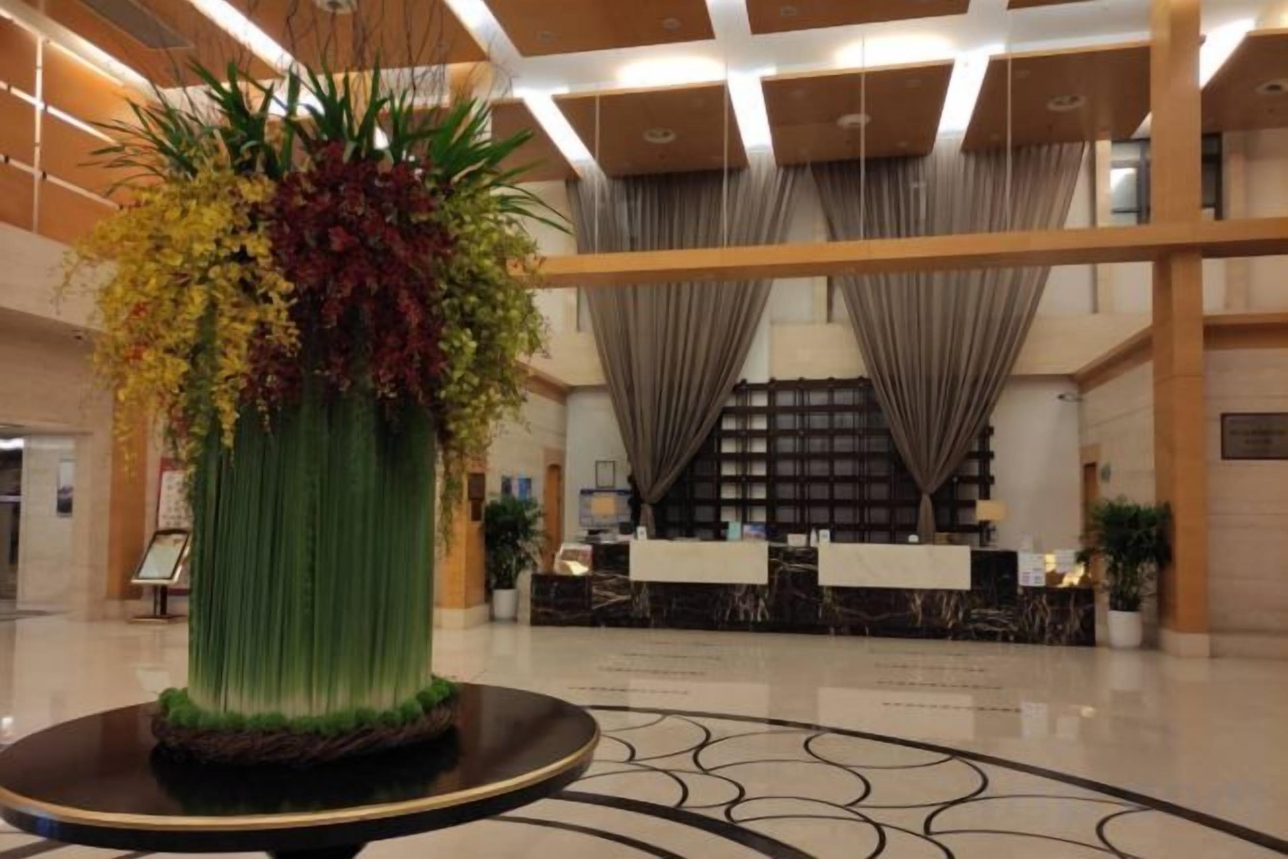 A lobby with a reception desk, a large decorative vase, and a patterned floor.