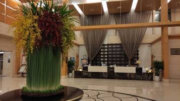 A lobby with a reception desk, a large decorative vase, and a patterned floor.