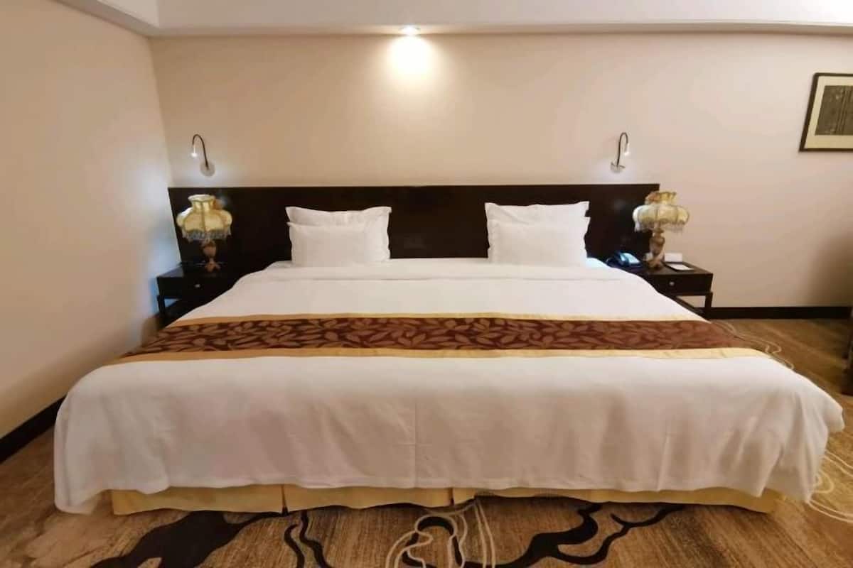 A hotel room with a large bed, two bedside tables, and a headboard.