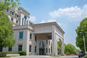 A large, historic building with a prominent archway entrance, multiple windows, and a well-maintained surrounding area. - ZTE Hotel, Nanjing (Nanjing)