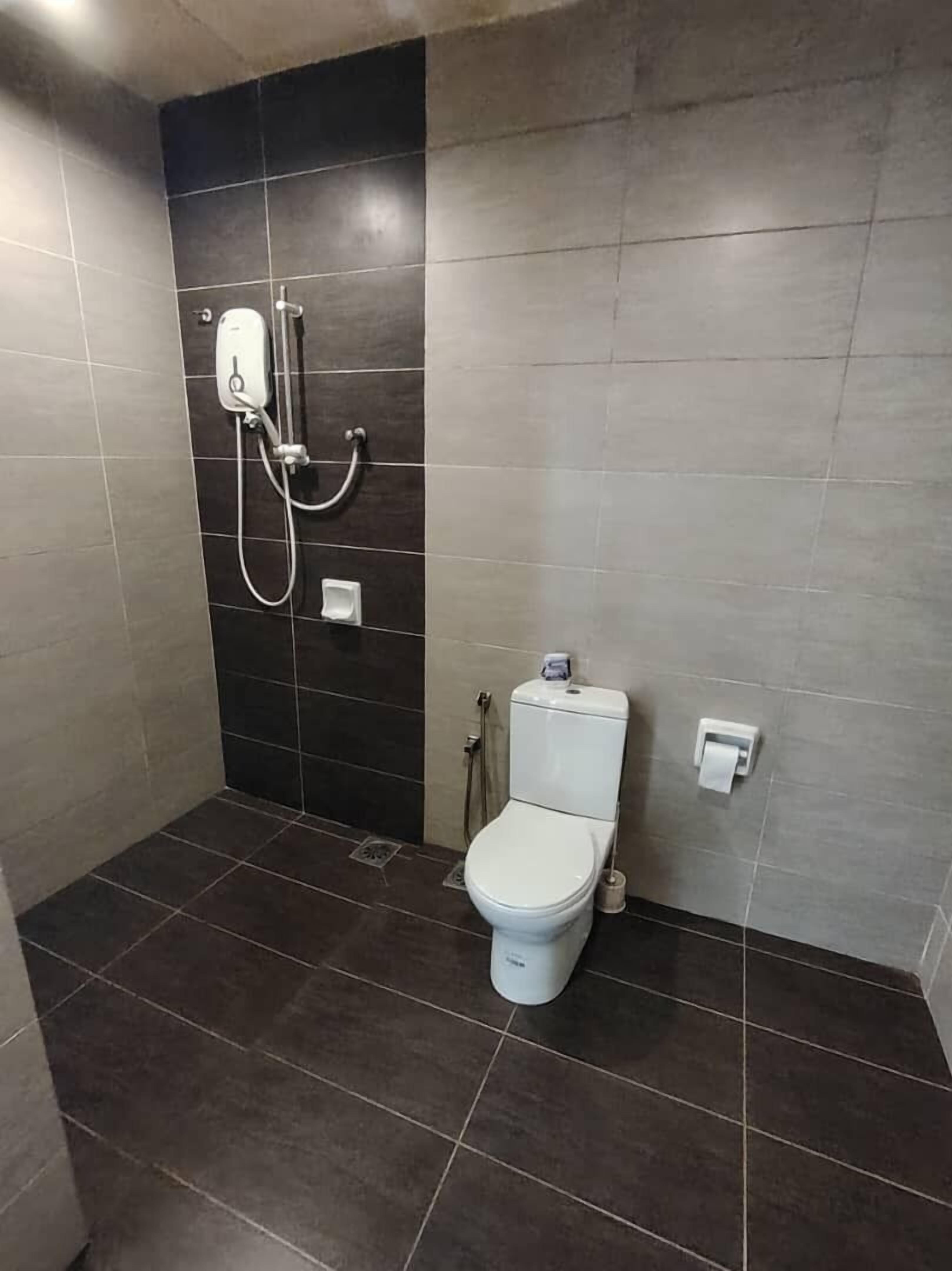 Een kleine, moderne badkamer met een toilet, een douche en een toiletrolhouder.