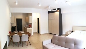 A modern hotel room with a sofa, a dining area with a table and chairs, a kitchenette, and a wardrobe. - Midhills at Genting by Self Check In (Genting Highlands)