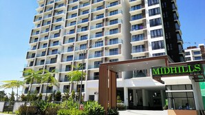 A multi-story hotel with a modern design, featuring balconies on each floor and a prominent entrance with a sign. - Midhills at Genting by Self Check In (Genting Highlands)