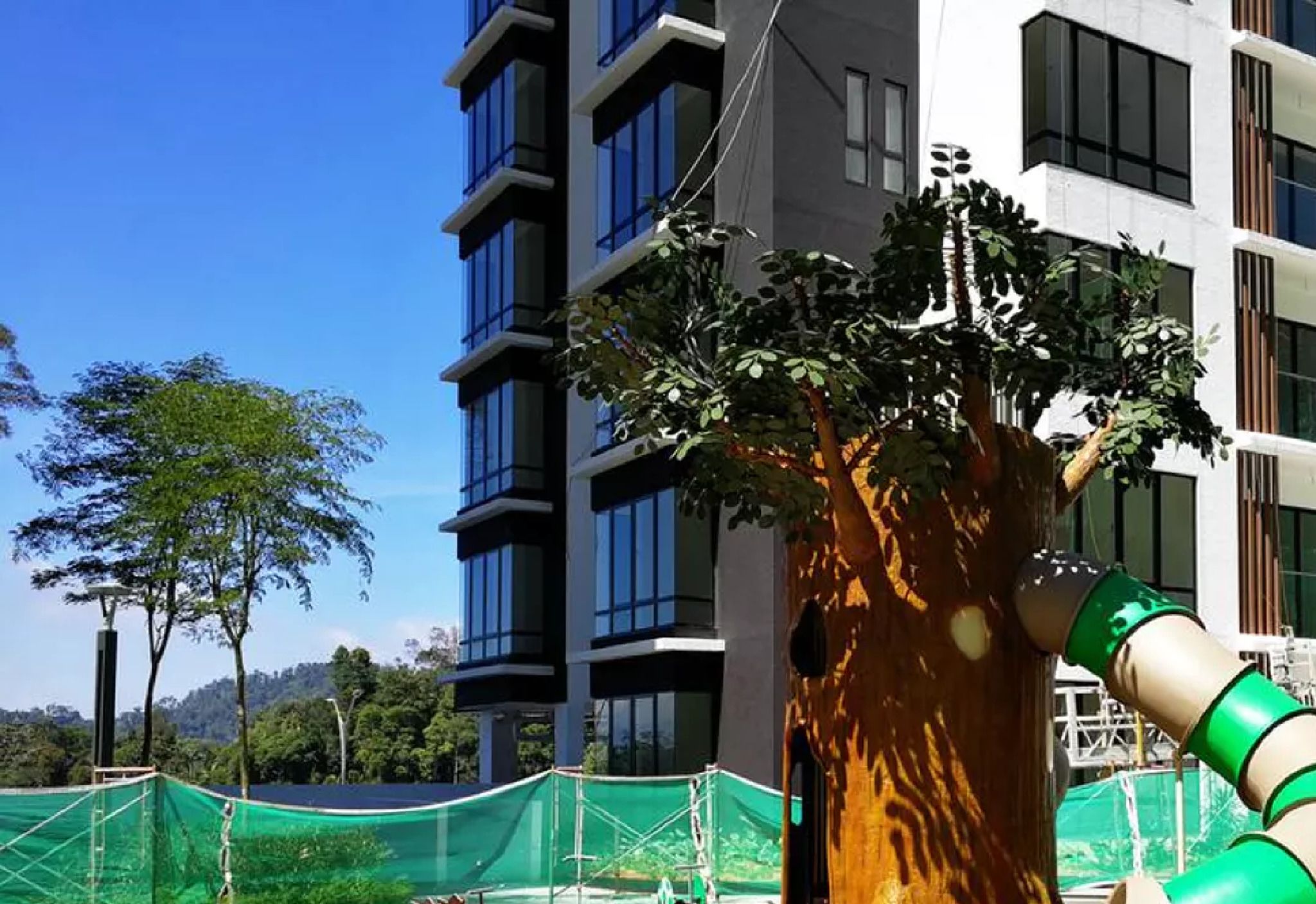 A modern building with multiple windows and a tree in front.