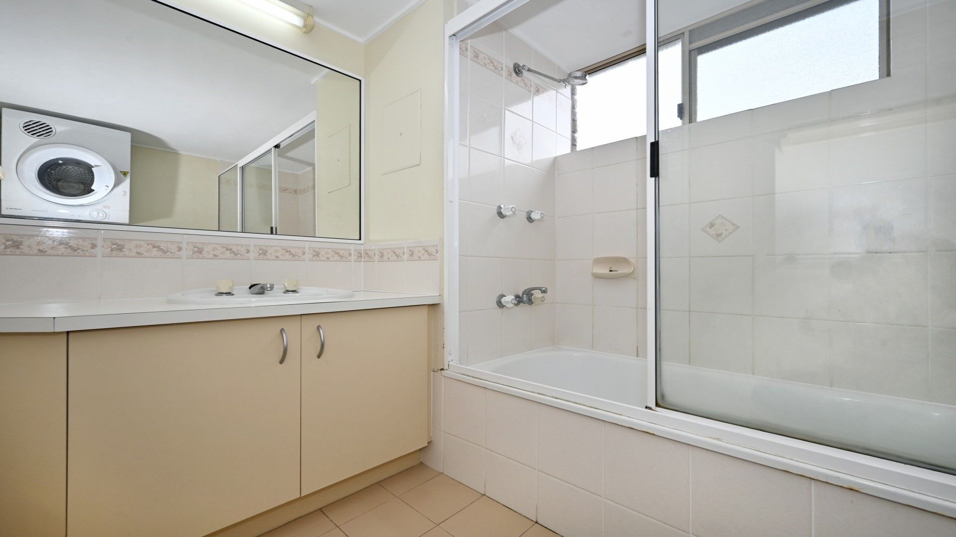A bathroom with a built-in washing machine, a bathtub, and a shower enclosure.