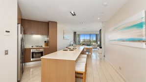 Een moderne keuken met een centraal eiland, roestvrijstalen apparatuur en uitzicht op de buitenruimte.