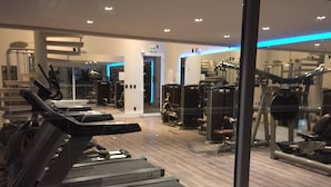 Ein Fitnessstudio mit Laufbändern, Kraftgeräten und einer Spiegelwand.