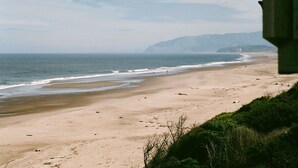 A beach with a clear view of the ocean and distant mountains. - Shearwater Beach Front Vacation Rental 3000 sqft (Depoe Bay)