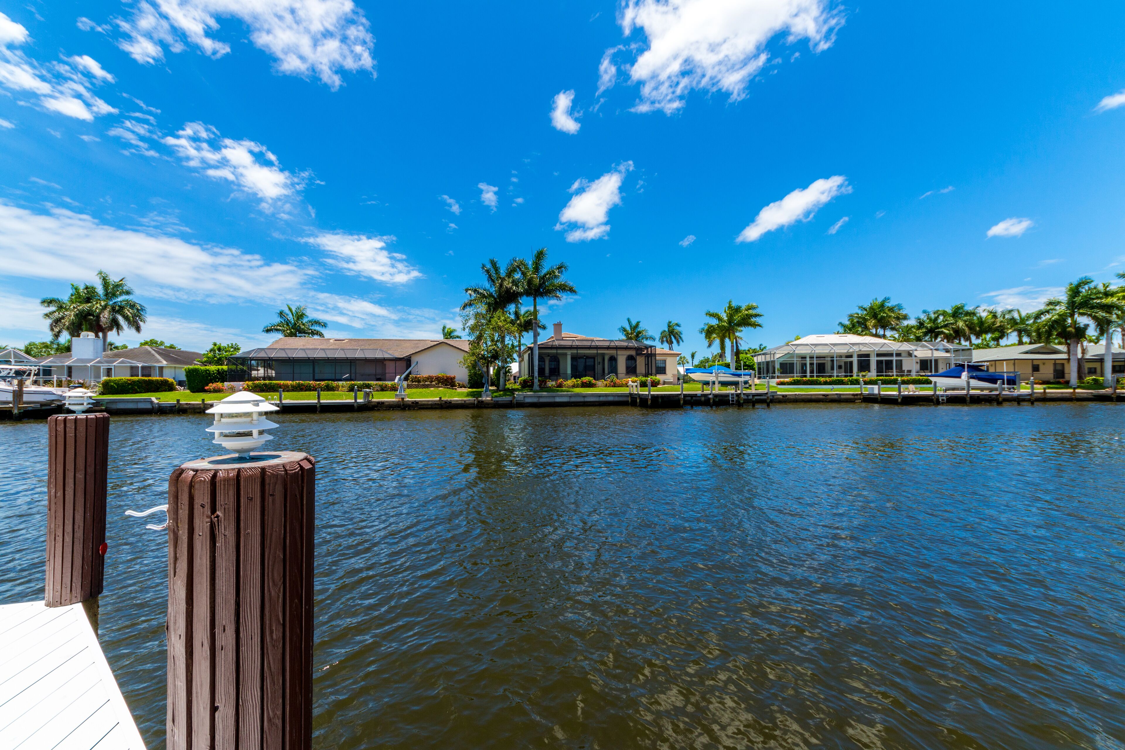 A waterfront property with a dock, palm trees, and a clear blue sky.