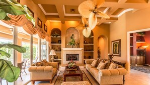 A spacious living room with a fireplace, comfortable seating, and a large ceiling fan. - Beautifully Furnished Tommy Bahama Inspired Home (Marco Island)