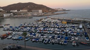 A marina with numerous boats docked, a road with cars, and buildings in the background. - Puerto Rico Gran Canaria: Beach and enjoyment at your fingertips (Mogán)