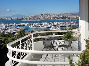 Ein Balkon mit Tisch und Stühlen mit Blick auf einen Yachthafen und zahlreiche Boote.