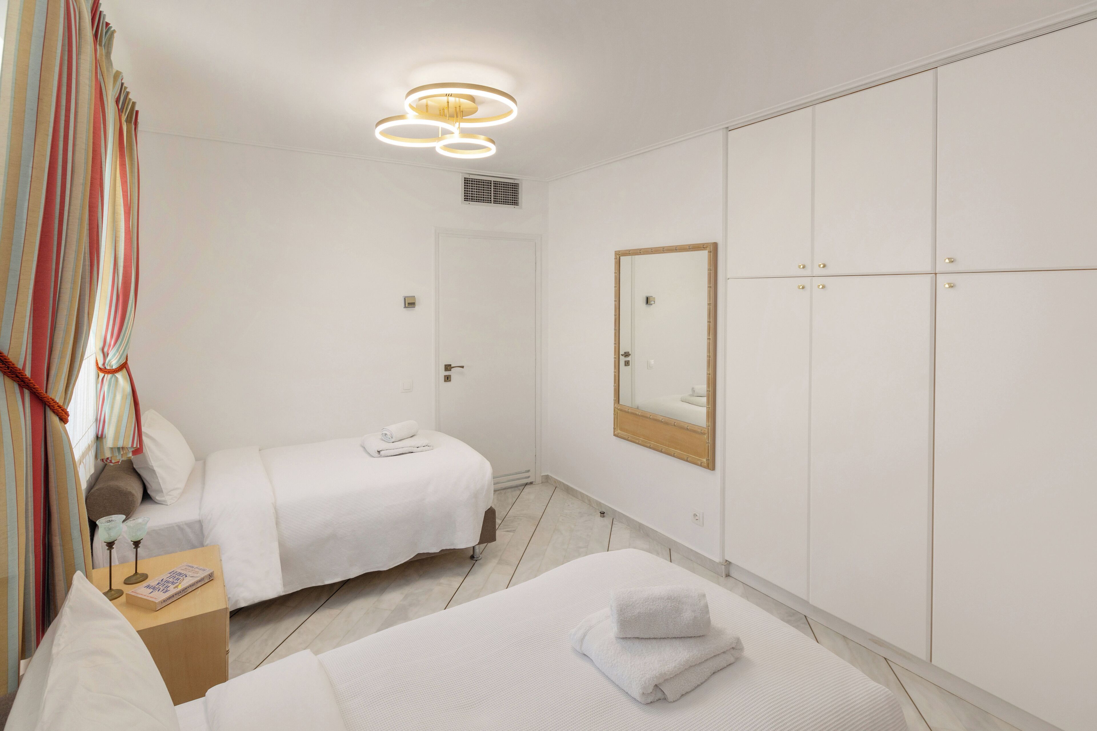 Ein Hotelzimmer mit zwei Betten, einem Kleiderschrank, einem Spiegel und einer Deckenleuchte.