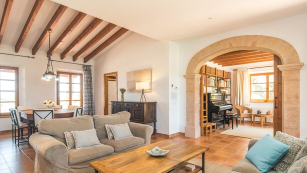 Amplia sala de estar con techo de madera, una mesa de comedor, un conjunto de sofás y un piano.