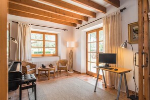 Relax in a spacious room with a comfortable seating area, desk, and piano, offering a view of lush greenery.