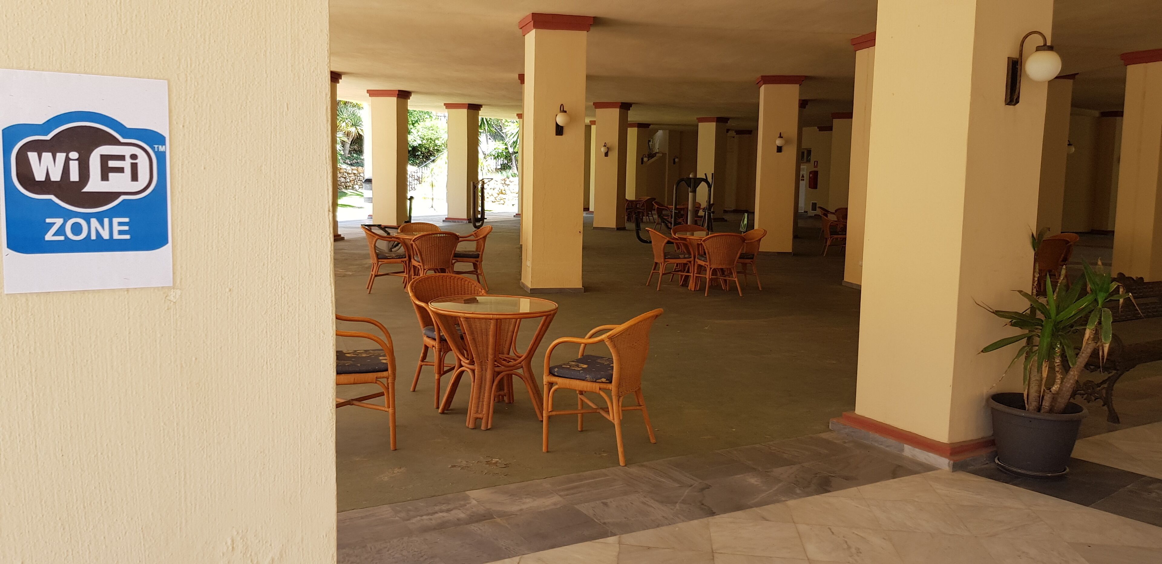 A covered outdoor area with wicker furniture and a Wi-Fi zone sign.