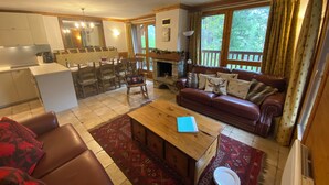 A cozy living room with a fireplace, a dining area, and a kitchen. - Arc 2000 Chalet, Peaceful Chalet By Slopes with Pool/Spa  (Bourg-Saint-Maurice)
