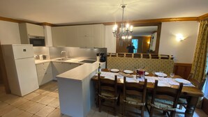 A compact kitchen with a central island, a dining table with chairs, and a built-in bench. - Arc 2000 Chalet, Peaceful Chalet By Slopes with Pool/Spa  (Bourg-Saint-Maurice)