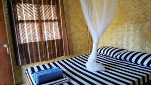 A room with a bed, a window with curtains, a mosquito net, and a blue towel. - Mount Avangan Eco Adventure Park (Coron)