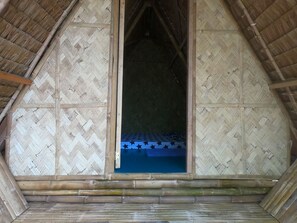 A room with a thatched roof, wooden walls, and a bed with a blue mattress and star-patterned bedding. - Mount Avangan Eco Adventure Park (Coron)