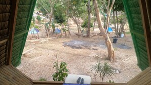 A room with a view of an outdoor area featuring trees, a fire pit, and several tents. - Mount Avangan Eco Adventure Park (Coron)