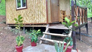 A small, single-story bamboo house with a porch and a wooden chair. - Mount Avangan Eco Adventure Park (Coron)