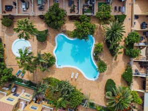 An aerial view of a resort with a large central pool, multiple smaller pools, and lush landscaping. - 3 bedroom villa in family complex with pools (Corralejo)