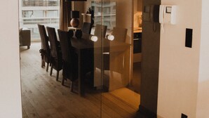 Ein modernes Interieur mit Essbereich, einer Glastrennwand und einer sichtbaren Küchenzeile.