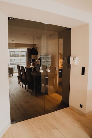 Ein modernes Interieur mit Essbereich, einer Glastrennwand und einer sichtbaren Küchenzeile.