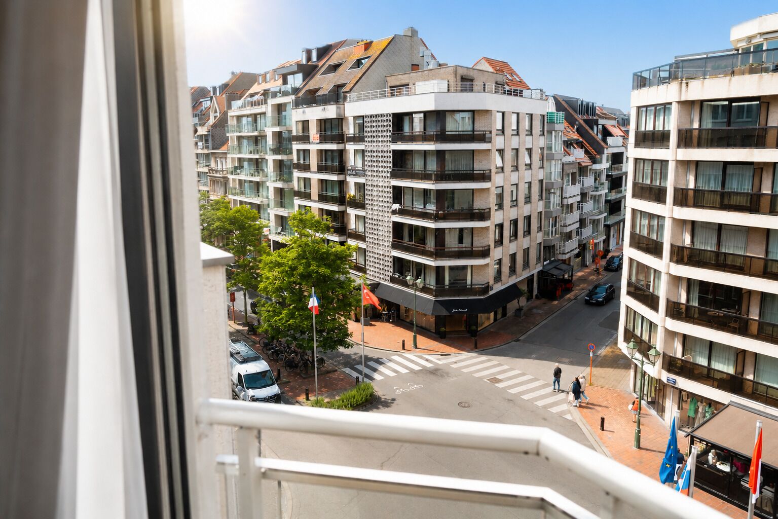 A multi-story building with balconies, a pedestrian crossing, and a street view.