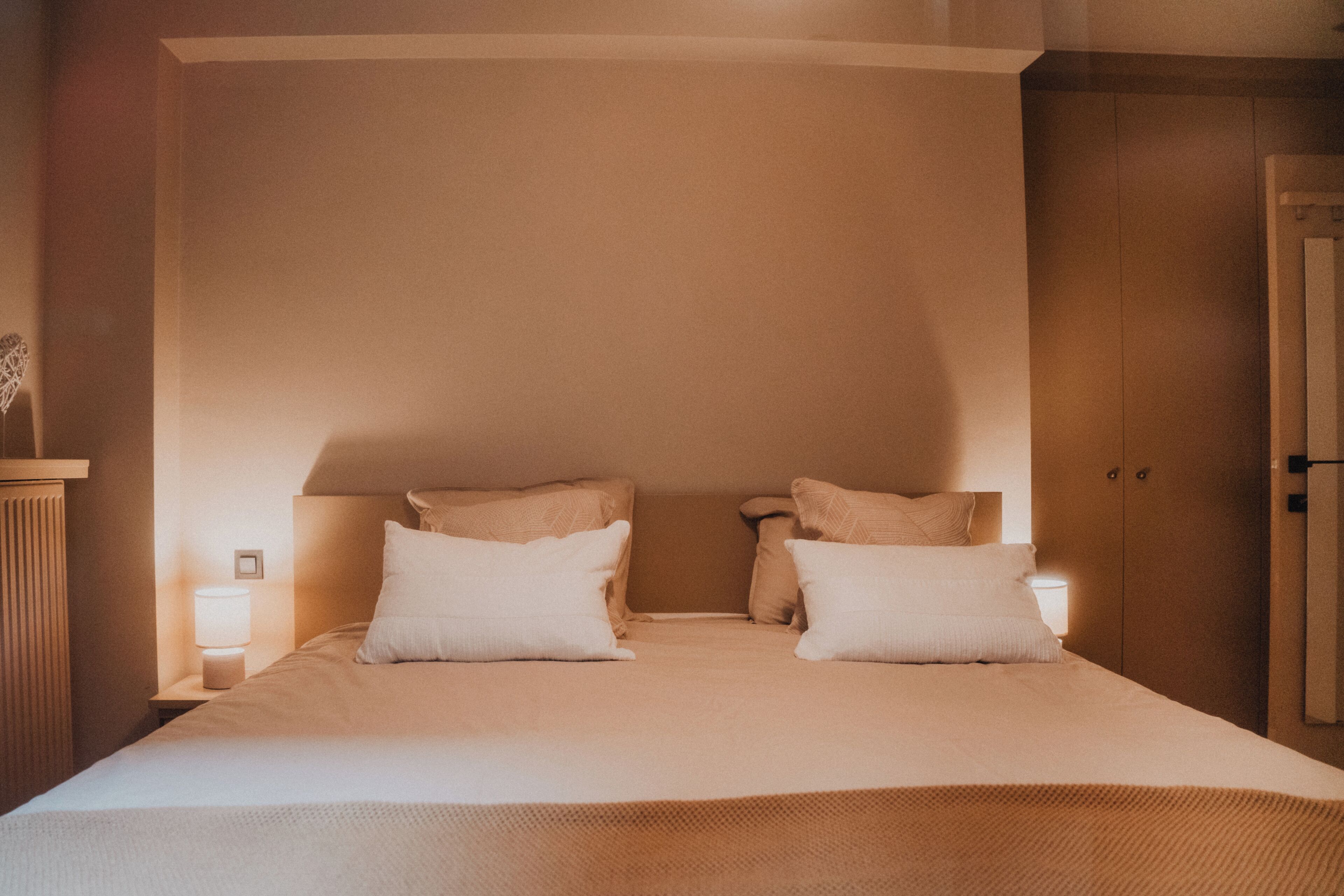 A neatly made bed with two pillows and a bedside lamp.